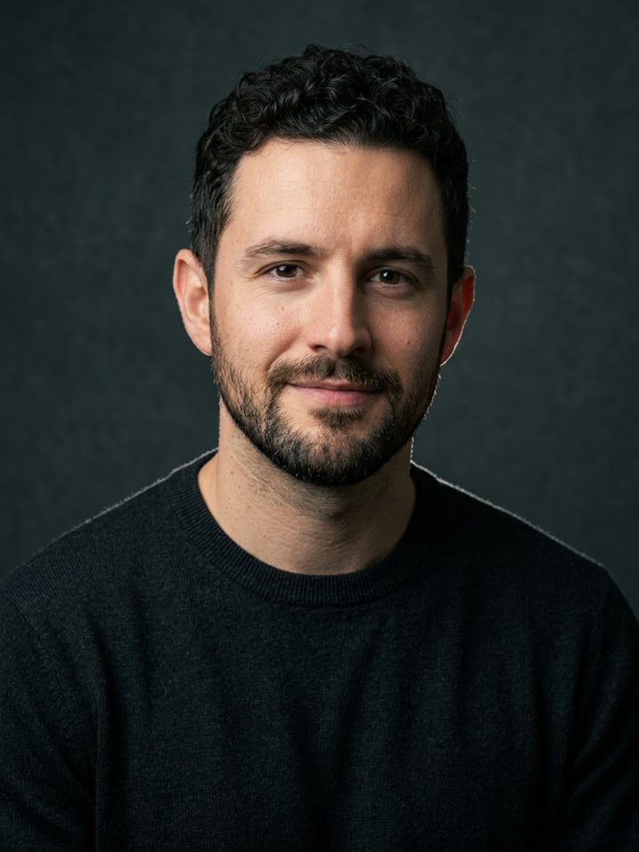 Dark studio portrait: the same man in a black top on a dark backdrop